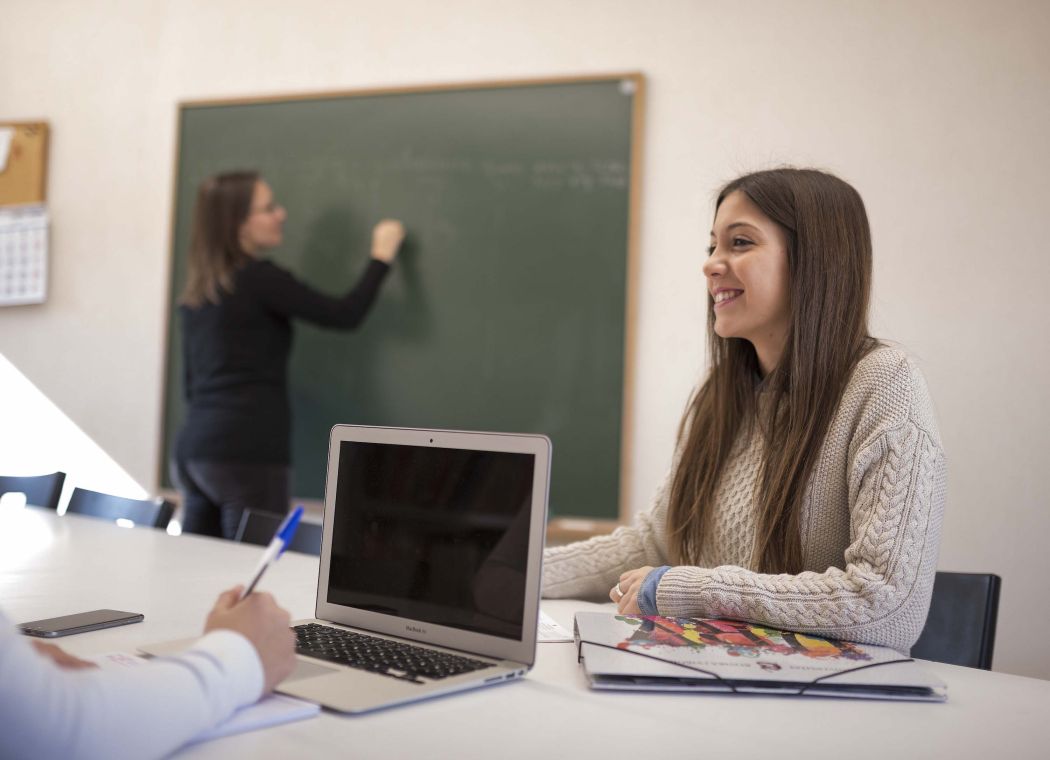 pretty girl smiling with laptop in a classroom